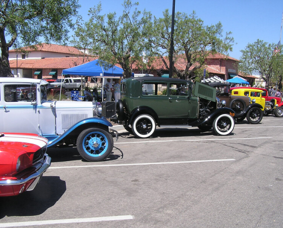 A line of classic cars parked on a street outside the Hitching Post